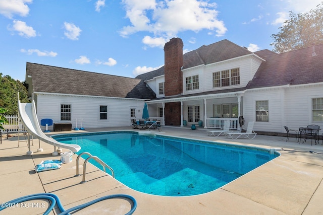 outdoor pool featuring a patio area, a water slide, and french doors