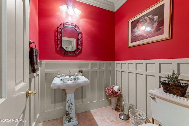 bathroom featuring ornamental molding, wainscoting, and a decorative wall