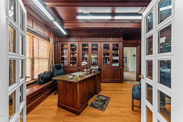 office space with crown molding, french doors, wood walls, and light wood finished floors