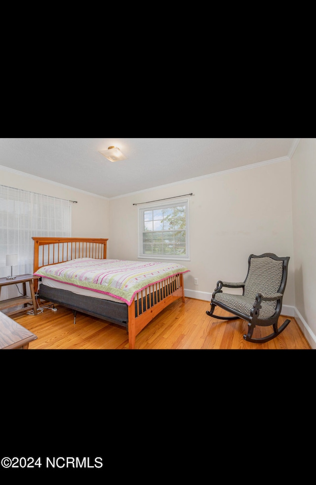 bedroom with light hardwood / wood-style flooring and ornamental molding