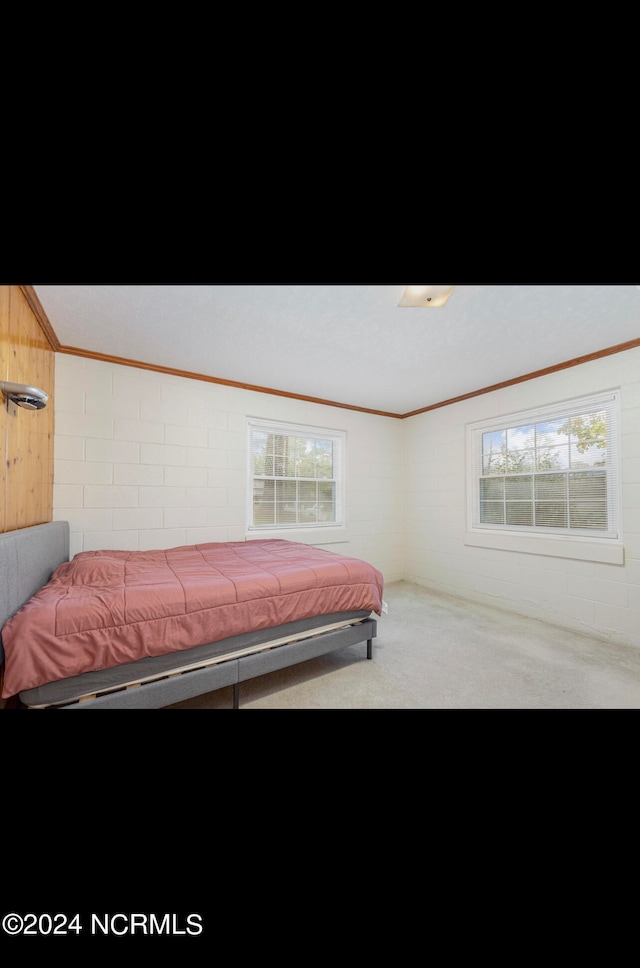 bedroom with wood walls, carpet flooring, and crown molding