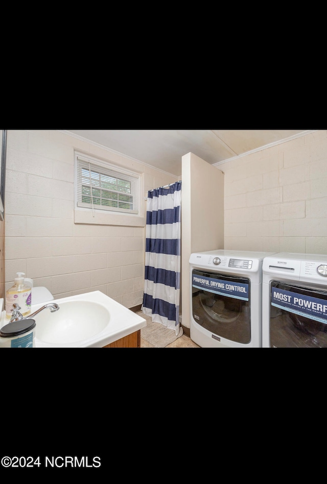 bathroom with tile walls, separate washer and dryer, a shower with shower curtain, and sink