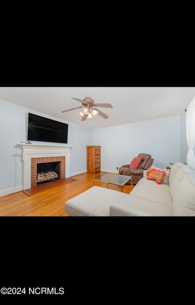 living room featuring hardwood / wood-style floors, ceiling fan, and a brick fireplace