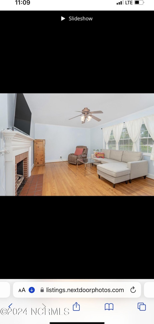 unfurnished living room featuring a brick fireplace, hardwood / wood-style flooring, and ceiling fan