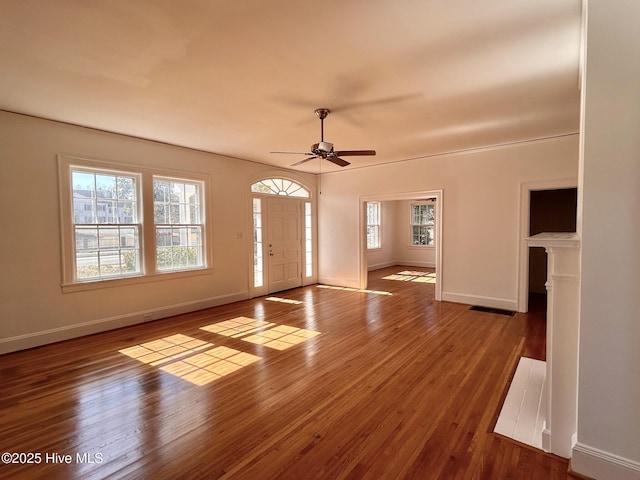 unfurnished living room featuring plenty of natural light, dark wood-type flooring, and ceiling fan