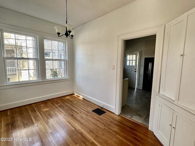 unfurnished dining area with hardwood / wood-style flooring and a chandelier