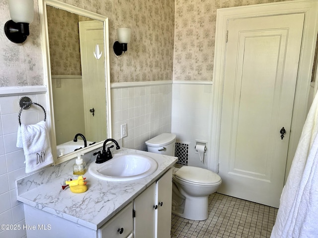 bathroom featuring vanity, tile patterned flooring, wainscoting, and wallpapered walls