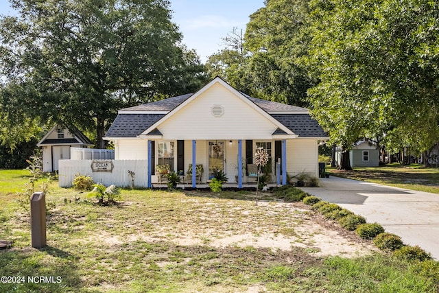 view of front facade featuring a porch, fence, and a shingled roof