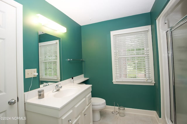 bathroom with tile patterned flooring, vanity, toilet, baseboards, and a stall shower