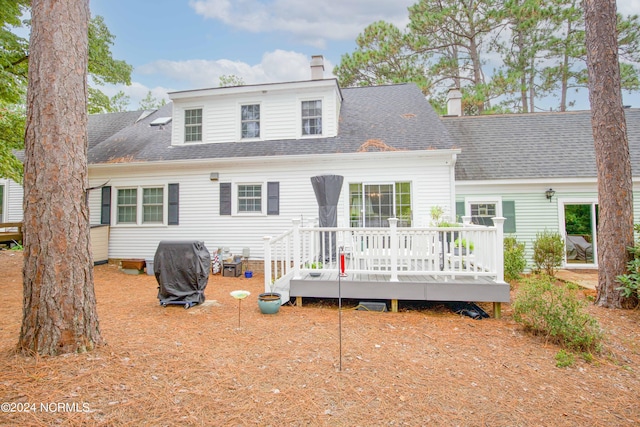 back of house featuring a chimney, a shingled roof, and a wooden deck