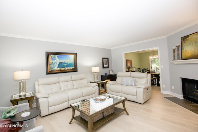 living area featuring an inviting chandelier, baseboards, crown molding, and light wood-type flooring