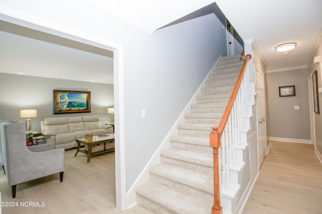 stairway with baseboards, ornamental molding, and wood finished floors