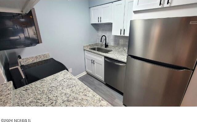 10166 Beach Dr SW Unit 5306, Calabash, NC 28467 - kitchen featuring appliances with stainless steel finishes, backsplash, light stone counters, wood finished floors, and white cabinets