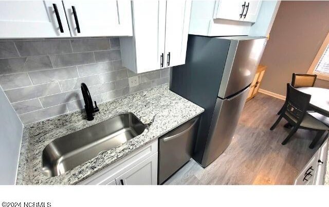 10166 Beach Dr SW Unit 5306, Calabash, NC 28467 - kitchen with appliances with stainless steel finishes, light wood-style flooring, white cabinetry, light stone counters, and tasteful backsplash