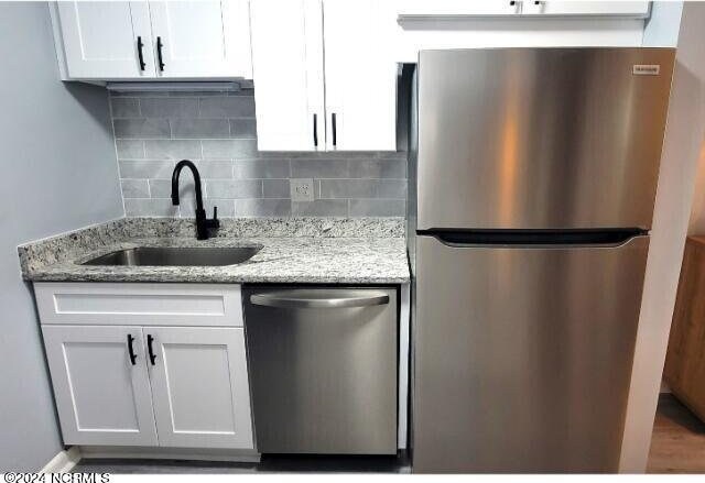 10166 Beach Dr SW Unit 5306, Calabash, NC 28467 - kitchen with appliances with stainless steel finishes, decorative backsplash, white cabinetry, and light stone counters