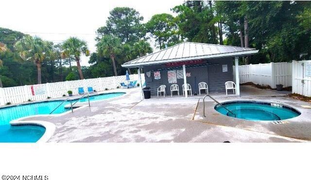 10166 Beach Dr SW Unit 5306, Calabash, NC 28467 - community pool featuring a community hot tub, a fenced backyard, a patio area, and view of wooded area