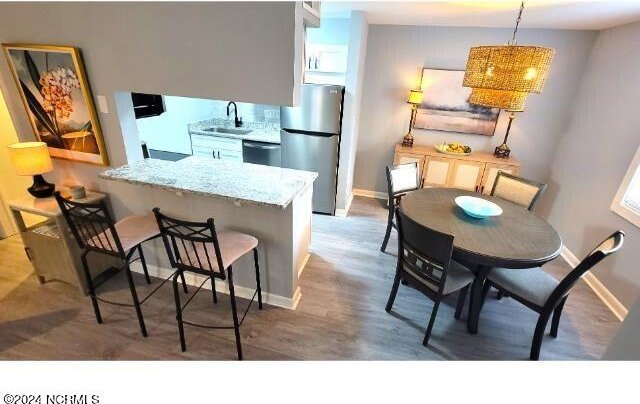 10166 Beach Dr SW Unit 5306, Calabash, NC 28467 - kitchen featuring stainless steel appliances, wood finished floors, a kitchen breakfast bar, light stone countertops, and a peninsula