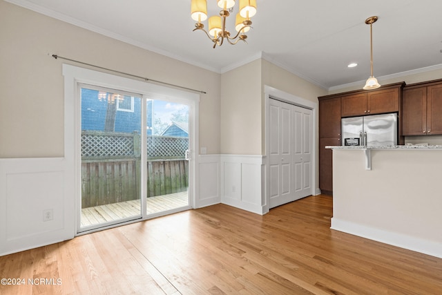 unfurnished dining area with light hardwood / wood-style flooring, crown molding, and a notable chandelier