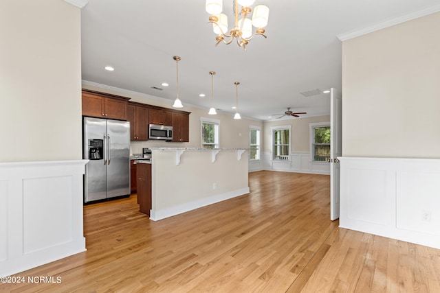 kitchen with a breakfast bar, appliances with stainless steel finishes, light hardwood / wood-style floors, and hanging light fixtures