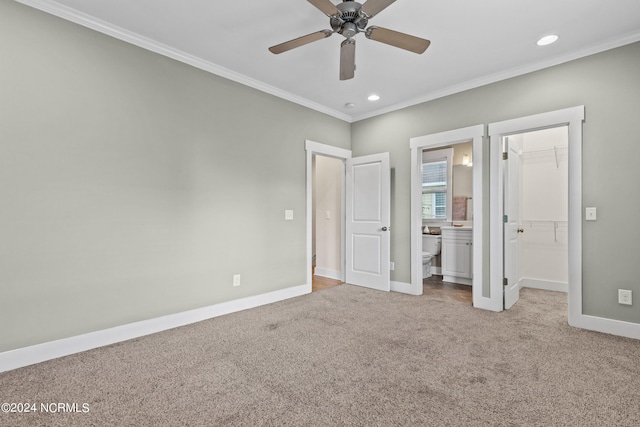 unfurnished bedroom with a closet, a walk in closet, light colored carpet, ceiling fan, and ensuite bathroom