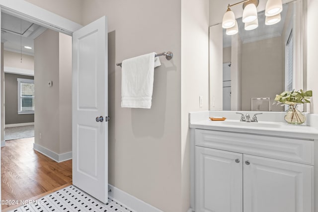 bathroom with wood-type flooring, crown molding, and vanity