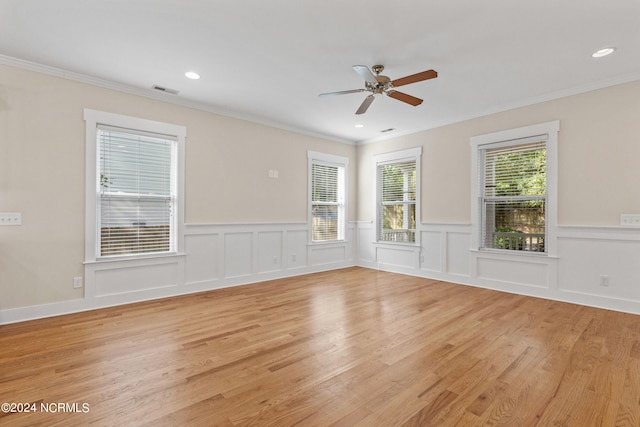 spare room featuring ornamental molding, light wood-type flooring, a healthy amount of sunlight, and ceiling fan