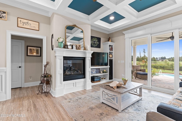 living room with ceiling fan, beamed ceiling, coffered ceiling, crown molding, and light hardwood / wood-style floors