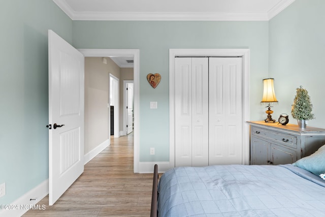 bedroom featuring light wood-type flooring, ornamental molding, and a closet