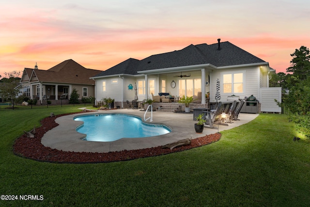 pool at dusk with a patio, a lawn, an outdoor living space, and ceiling fan