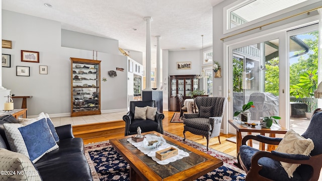 living room with ornate columns, a textured ceiling, and light hardwood / wood-style floors