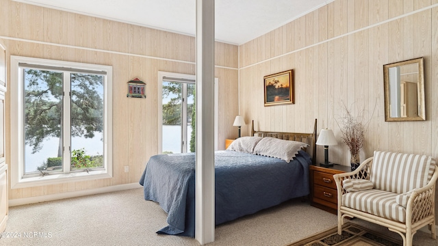 bedroom with multiple windows, wooden walls, and carpet floors