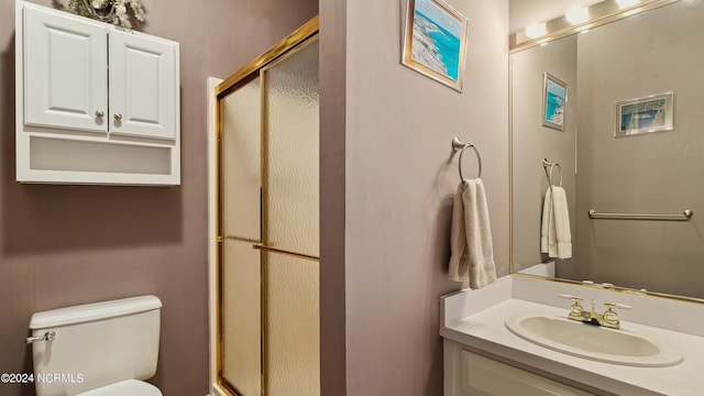 bathroom featuring a shower with shower door, vanity, and toilet