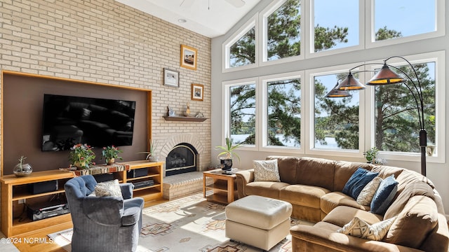 living room featuring high vaulted ceiling, ceiling fan, and a brick fireplace