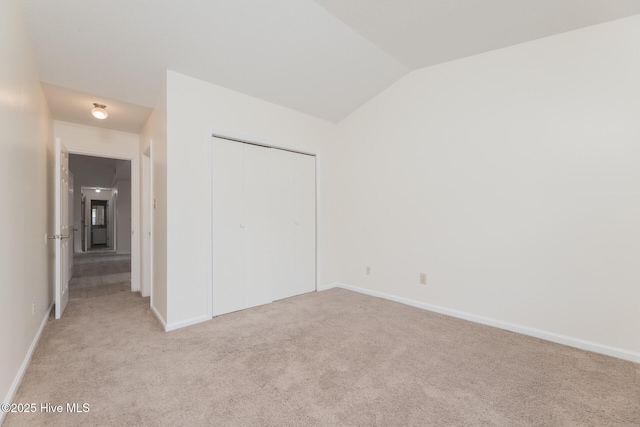 unfurnished bedroom with a closet, lofted ceiling, and light carpet