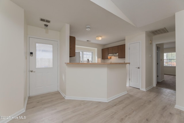 kitchen with kitchen peninsula, a healthy amount of sunlight, and light wood-type flooring