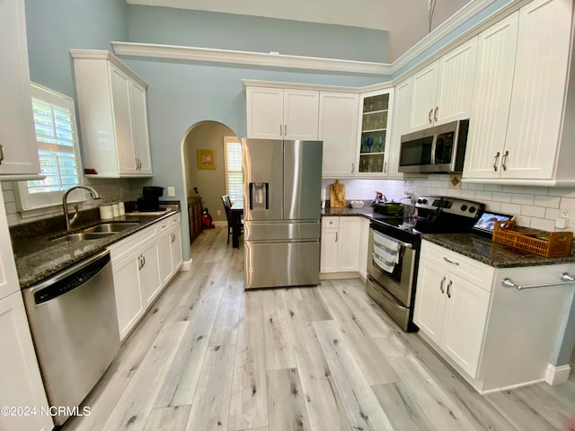 kitchen featuring light hardwood / wood-style floors, backsplash, stainless steel appliances, dark stone counters, and sink