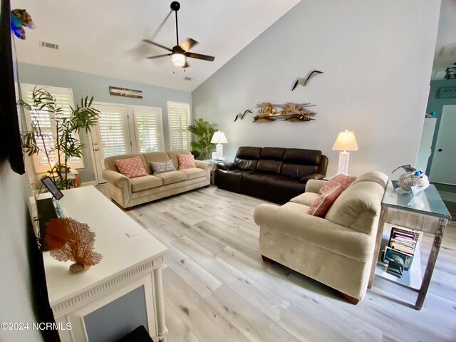 living room with ceiling fan, light hardwood / wood-style floors, and vaulted ceiling