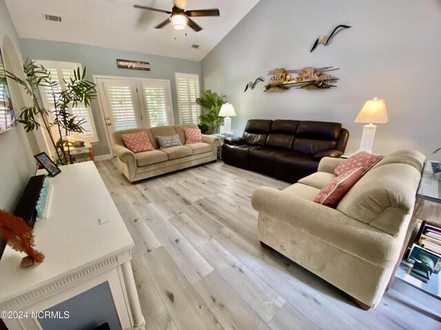 living room with ceiling fan, vaulted ceiling, and light hardwood / wood-style floors