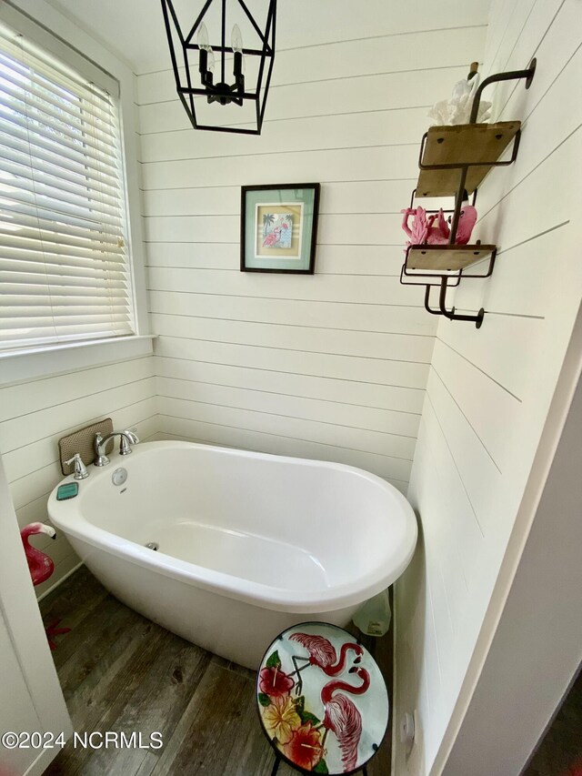 bathroom featuring wooden walls, hardwood / wood-style flooring, and a bathtub