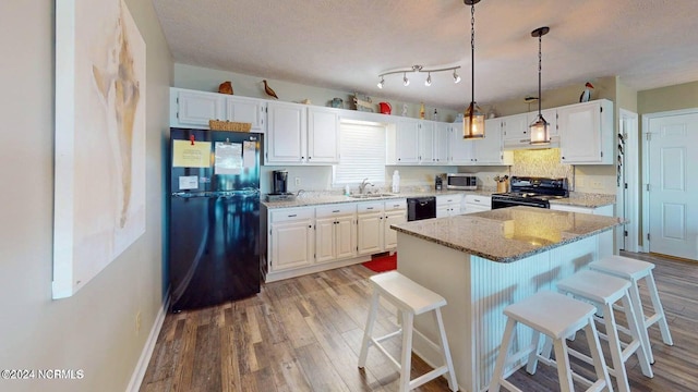 1514 Carolina Beach Ave N Unit 1 & 2, Carolina Beach, NC 28428 - kitchen featuring black appliances, light wood-style floors, white cabinetry, light stone countertops, and a kitchen island