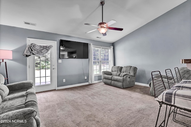 carpeted living room with ceiling fan and vaulted ceiling