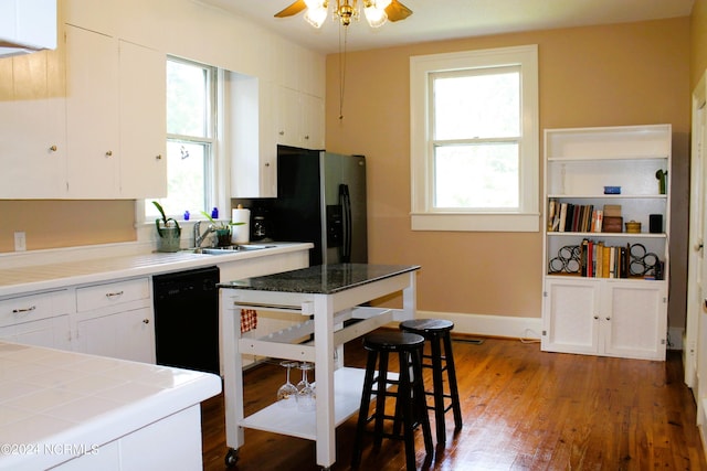 kitchen featuring ceiling fan, white cabinets, sink, tile countertops, and dark hardwood / wood-style floors