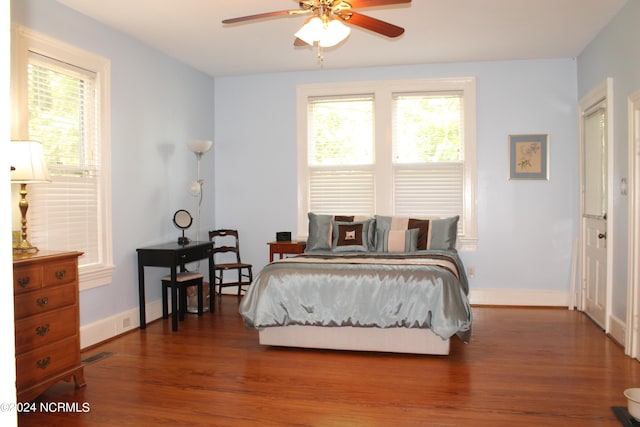 bedroom featuring multiple windows, dark hardwood / wood-style floors, and ceiling fan