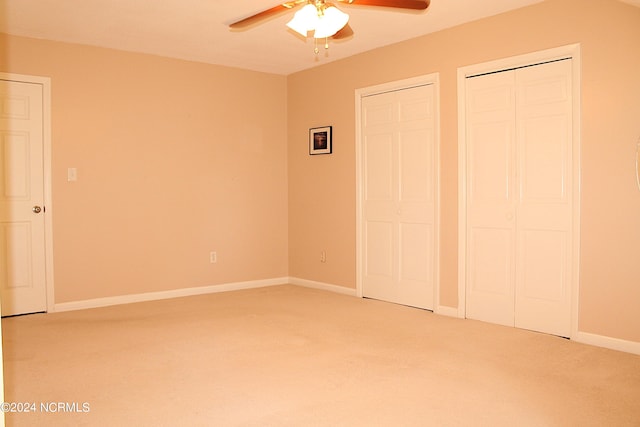 unfurnished bedroom featuring ceiling fan, two closets, and carpet flooring