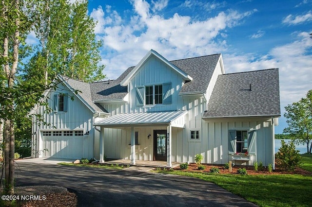 modern farmhouse with a front yard, a garage, and a porch