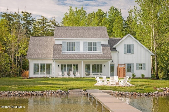 back of house featuring a patio, a yard, and a water view