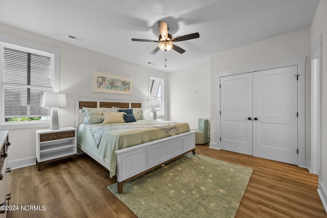 bedroom featuring ceiling fan, hardwood / wood-style flooring, and multiple windows