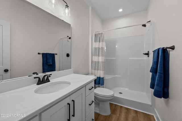 bathroom with hardwood / wood-style floors, walk in shower, vanity, and toilet