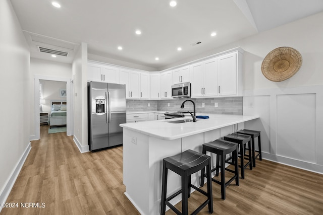 kitchen featuring white cabinets, appliances with stainless steel finishes, light hardwood / wood-style floors, and kitchen peninsula