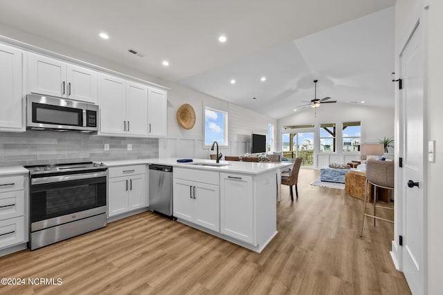 kitchen with appliances with stainless steel finishes, white cabinetry, lofted ceiling, ceiling fan, and sink